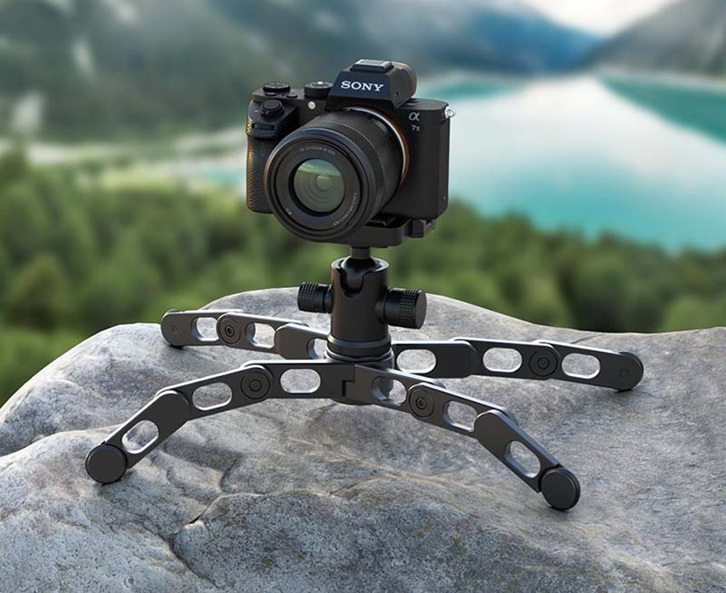 A camera set up on a tripod situated on a rock in nature.